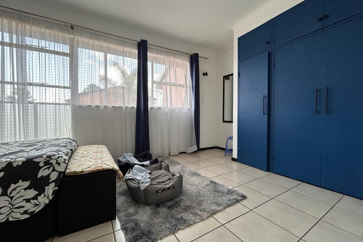 A bedroom featuring large windows with natural light, tiled flooring, and built-in blue cabinetry providing ample storage space.