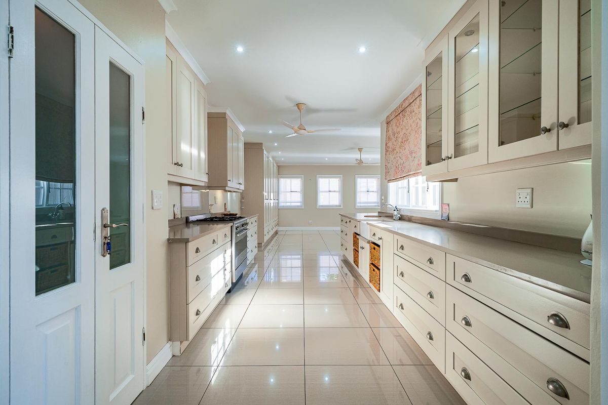 A spacious, well-lit kitchen featuring extensive cabinetry, stone countertops, a built-in gas stove, and polished floor tiles.
