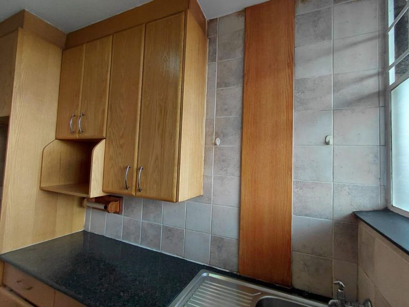 A functional kitchen area featuring laminate cabinetry, stone countertops, and a stainless steel sink with a tiled backsplash.