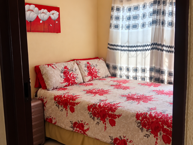 A compact bedroom featuring neutral wall tones and tiled flooring, providing a functional space with natural light through the window.