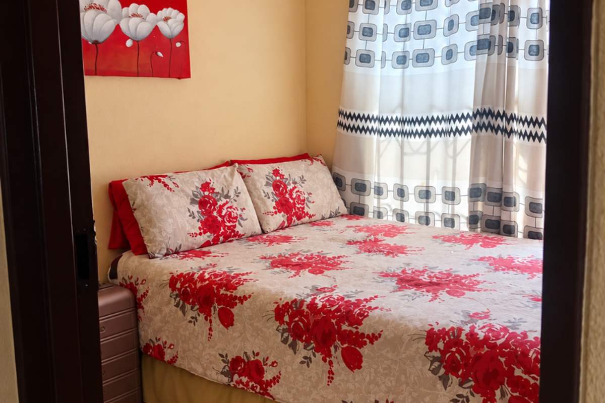 A compact bedroom featuring neutral wall tones and tiled flooring, providing a functional space with natural light through the window.