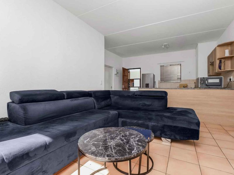 Open plan living area featuring tiled flooring and a functional kitchen with stone countertops and built-in cabinetry.
