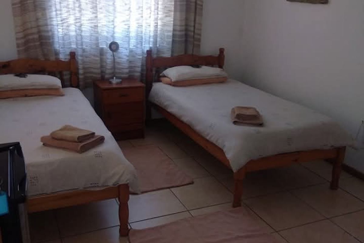 A functional bedroom featuring tiled flooring, a wall-mounted air conditioning unit, and a drop ceiling with integrated ventilation.