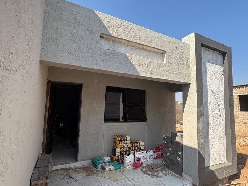 An unfinished patio area featuring tiled flooring and textured plaster walls, currently undergoing final construction and finishing work.
