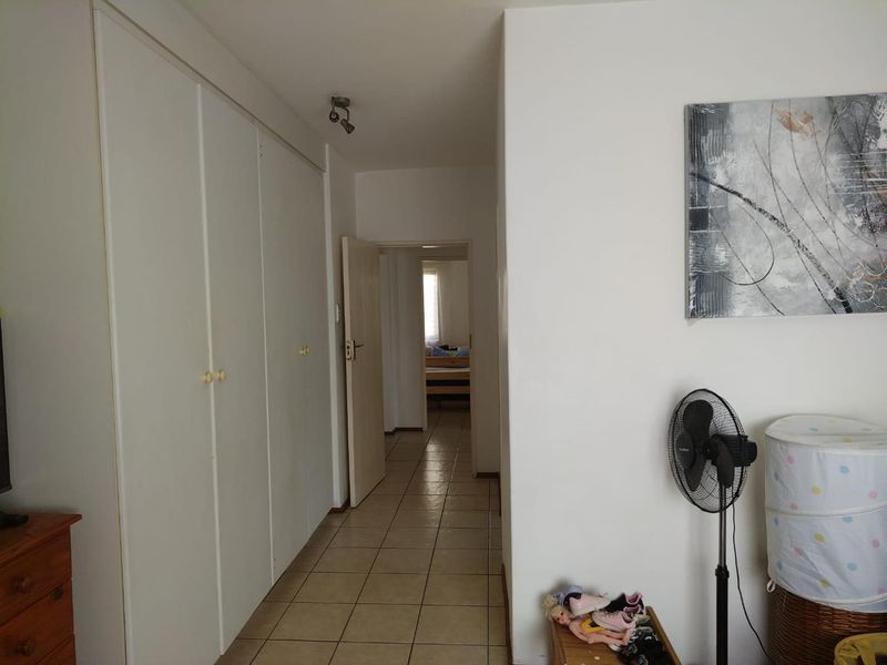 A functional hallway featuring tiled flooring and extensive built-in cupboard storage, providing a clean transition between living spaces.