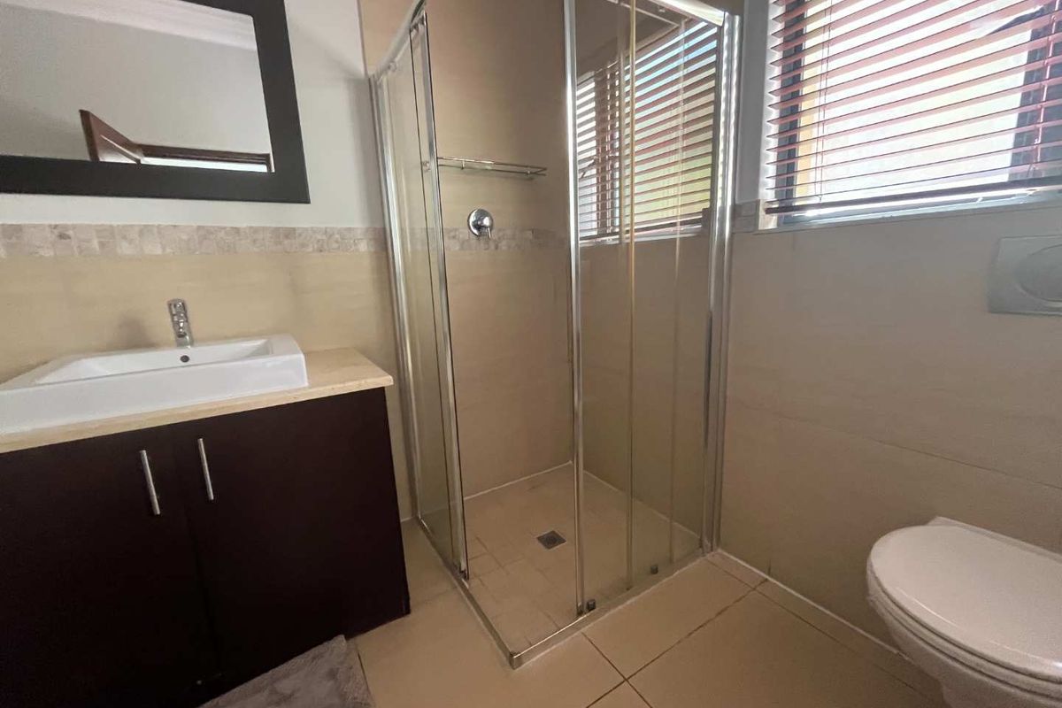 A functional bathroom featuring a glass-enclosed shower, a modern vanity with a vessel sink, and a wall-mounted toilet.