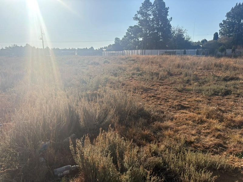 A vacant residential plot featuring natural vegetation and perimeter fencing, offering a blank canvas for future development.