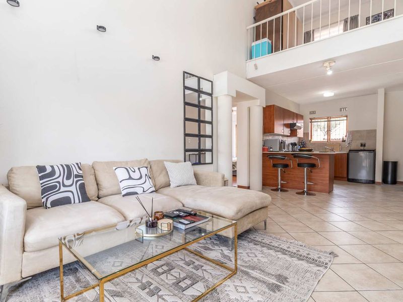 Spacious open-plan living area featuring a kitchen with island, tiled flooring, and a mezzanine level overlooking the main living space.
