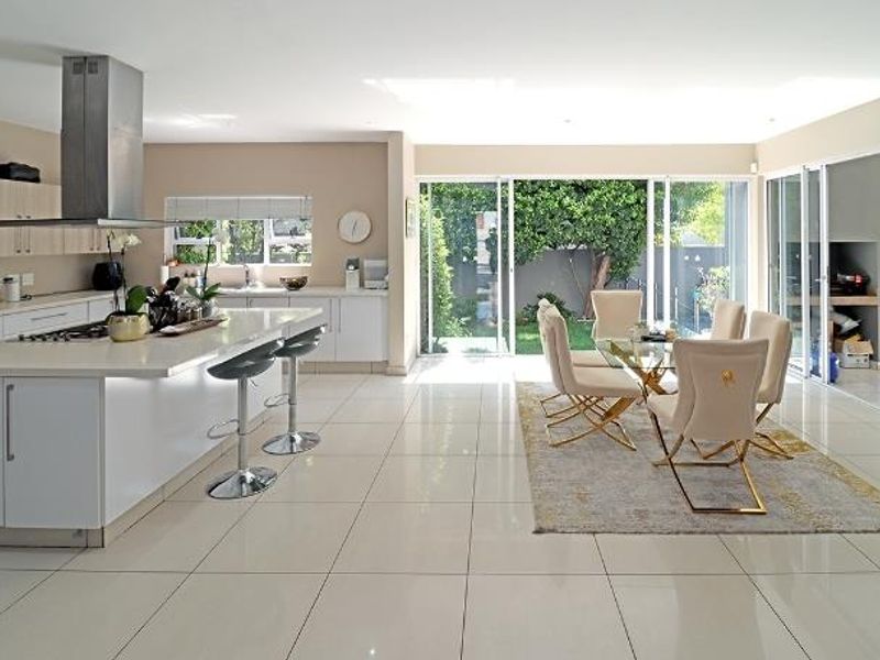 Spacious open-plan kitchen and dining area featuring modern cabinetry, a central island, and large sliding doors opening to a private garden patio.