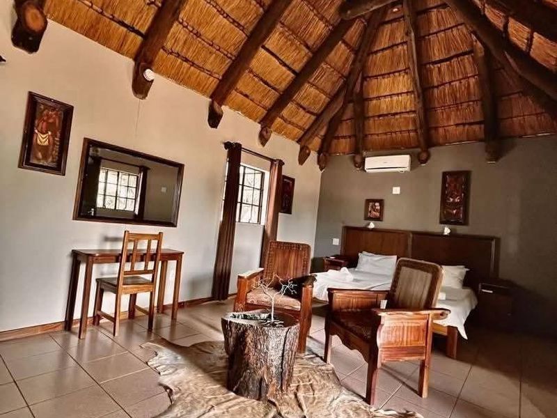 Spacious bedroom featuring a traditional thatched roof with exposed timber rafters, tiled flooring, and a wall-mounted air conditioning unit.
