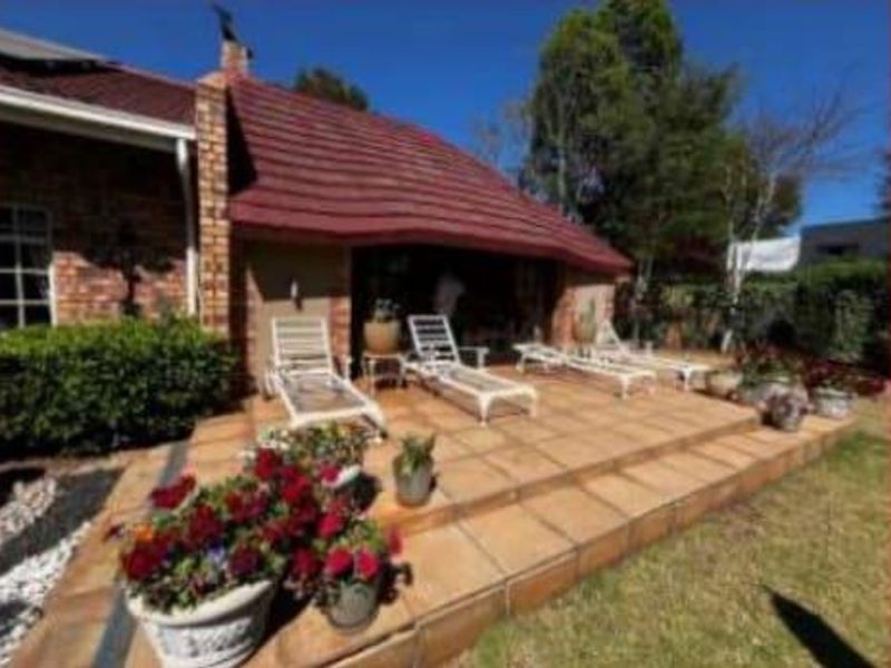 A covered outdoor patio area featuring tiled flooring and a brick chimney, providing a pleasant space for outdoor relaxation.