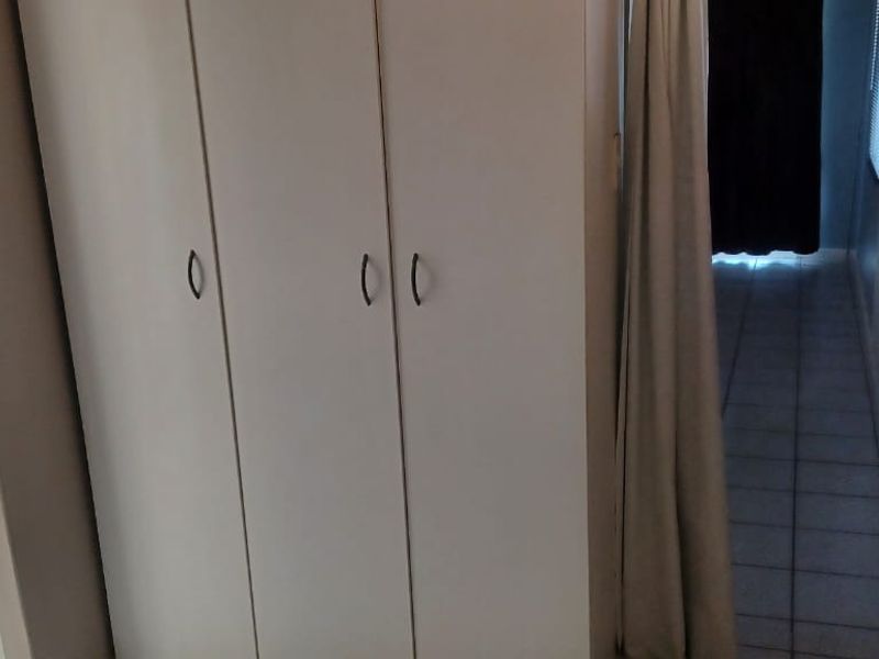 A functional hallway area featuring built-in storage cupboards and tiled flooring, providing access to adjacent rooms including a bathroom.