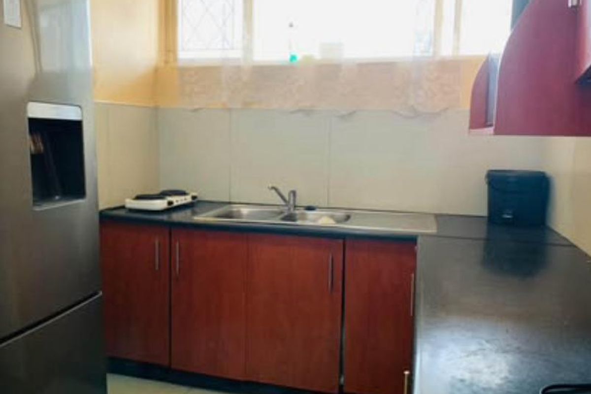 A functional kitchen area featuring dark laminate cabinetry, a double basin sink, and a window providing natural light.
