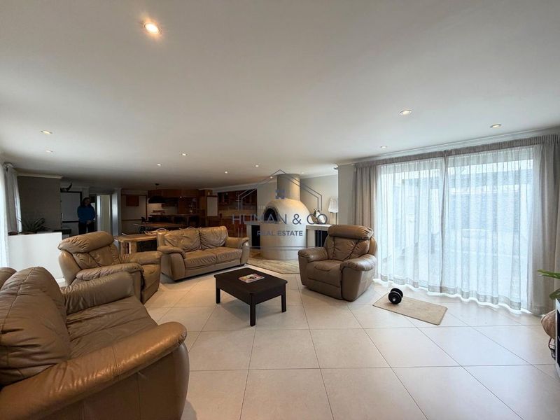 Spacious open-plan living area featuring tiled floors, recessed lighting, and a unique built-in pizza oven, with direct access to the outdoor space.