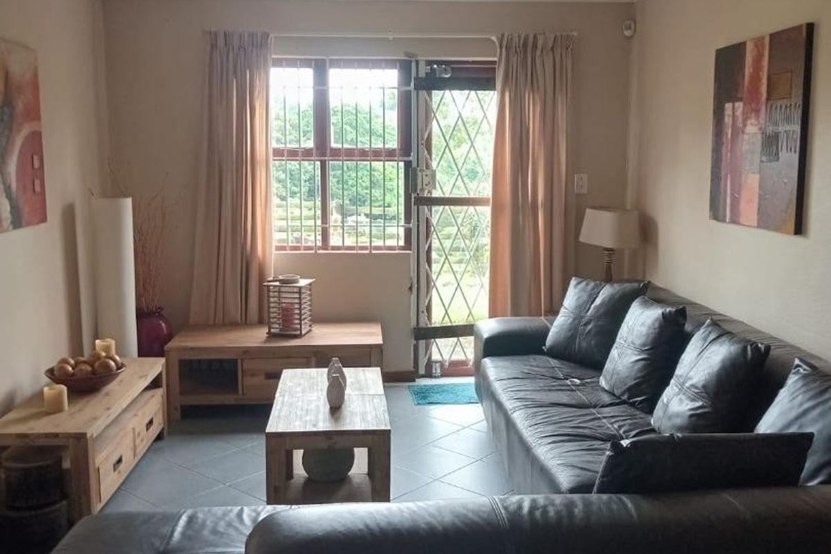 A comfortable living room featuring tiled flooring, natural light through a window with security bars, and direct access to the exterior via a security gate.
