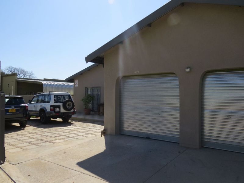 Exterior view of a double garage with roller shutter doors and a paved driveway area.