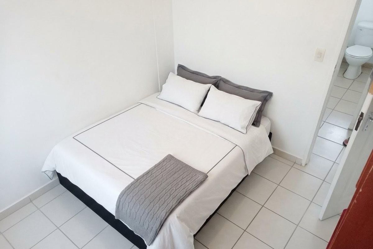 A compact bedroom featuring tiled flooring and direct access to an en-suite bathroom.