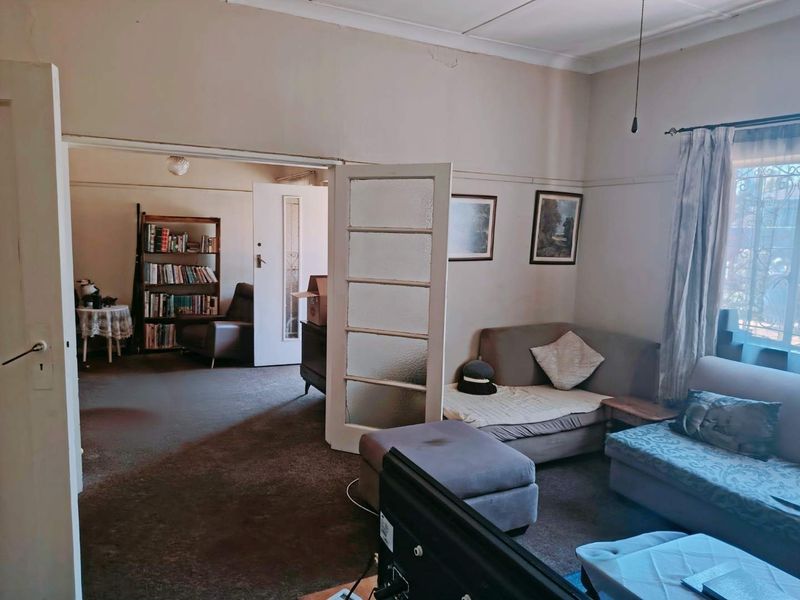 A living room featuring classic coved ceilings and picture rails, connected to an adjacent room via glass-paneled french doors.