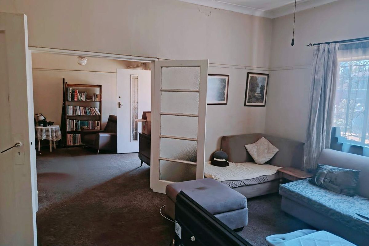 A living room featuring classic coved ceilings and picture rails, connected to an adjacent room via glass-paneled french doors.