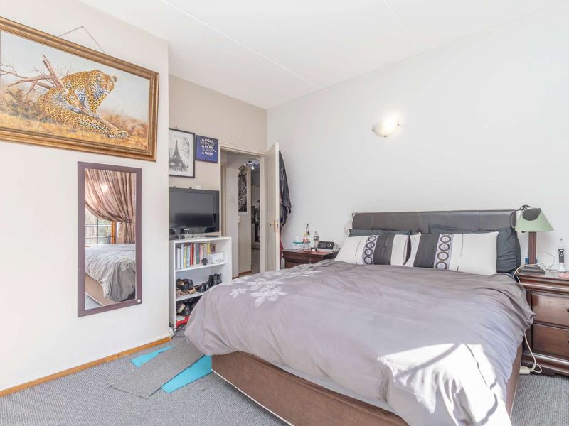 A bedroom featuring neutral walls and carpet flooring, currently furnished with a bed and bedside tables.