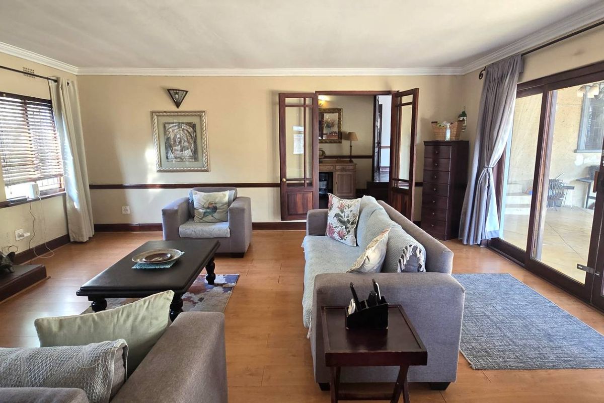 Spacious living room featuring warm wooden flooring, a traditional fireplace, and large sliding glass doors providing seamless access to the outdoor patio area.