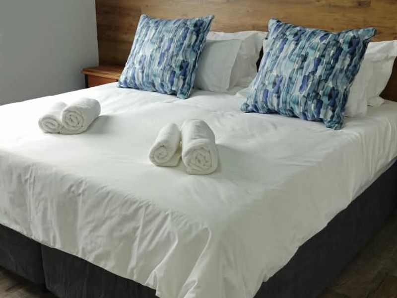 A well-maintained bedroom featuring wood-look laminate flooring and a modern built-in headboard with integrated wall-mounted lighting.