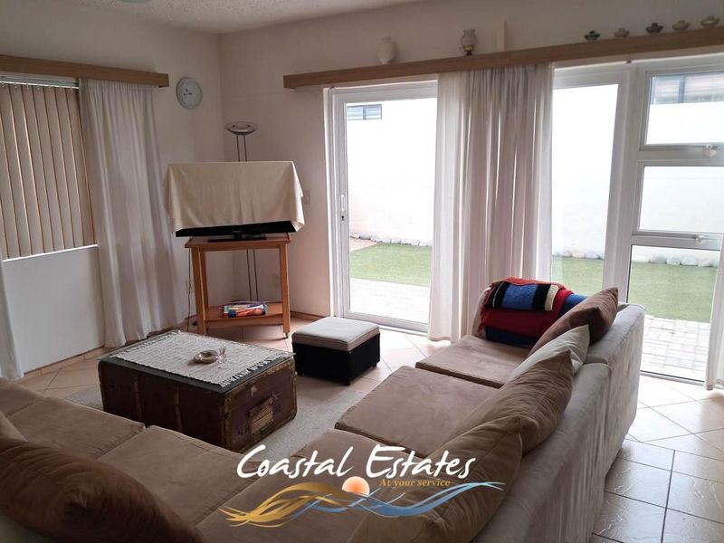 A living room featuring tiled flooring and large sliding glass doors that provide direct access to the outdoor patio area.