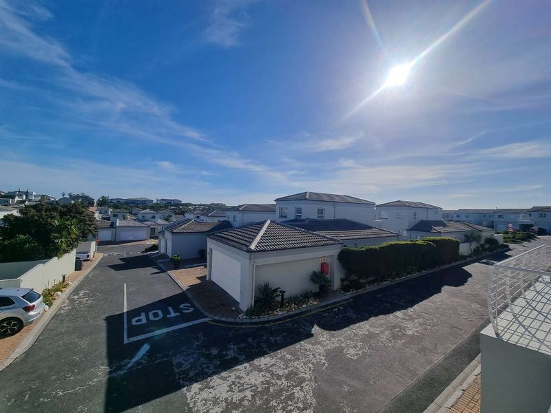 An elevated aerial view of a townhouse complex featuring multiple units with tiled roofs, paved driveways, and established boundary walls.