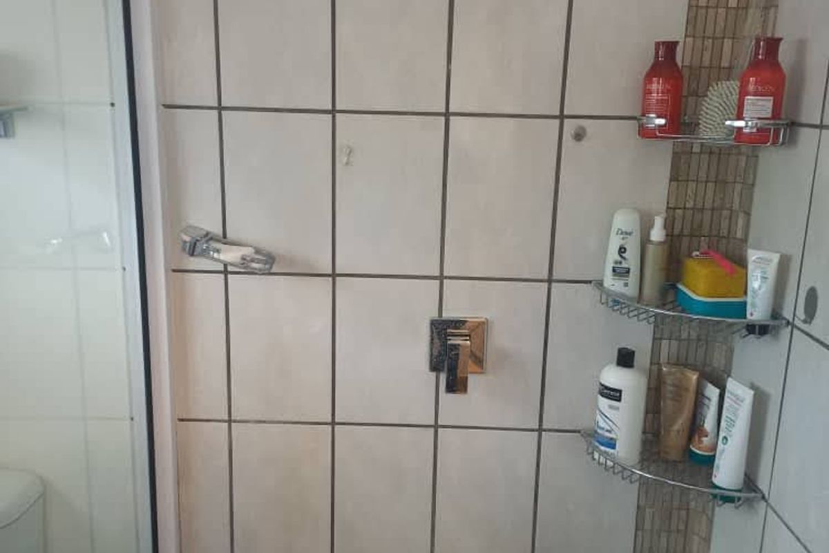 A functional shower enclosure featuring tiled walls with a decorative mosaic accent strip and a glass door.