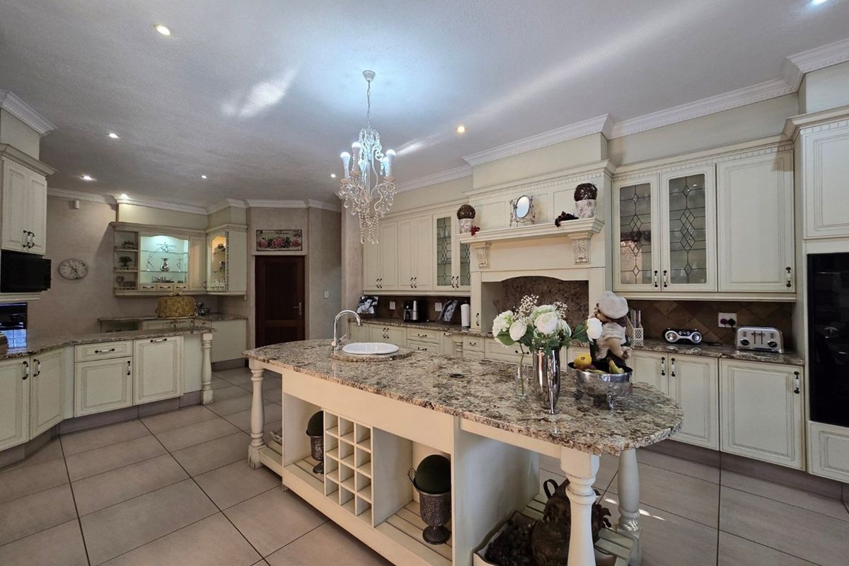 Spacious traditional kitchen featuring cream cabinetry, granite countertops, a large central island with integrated wine storage, and decorative crown molding.