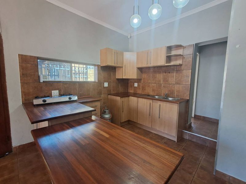 Functional kitchen featuring wooden countertops, laminate cabinetry, tiled backsplash, and a gas hob, offering a practical layout for meal preparation.