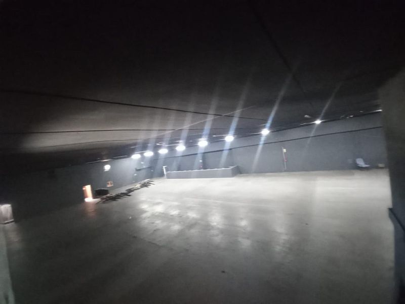 A large, open-plan industrial utility space featuring concrete flooring and high ceilings, suitable for storage, workshop, or warehouse operations.