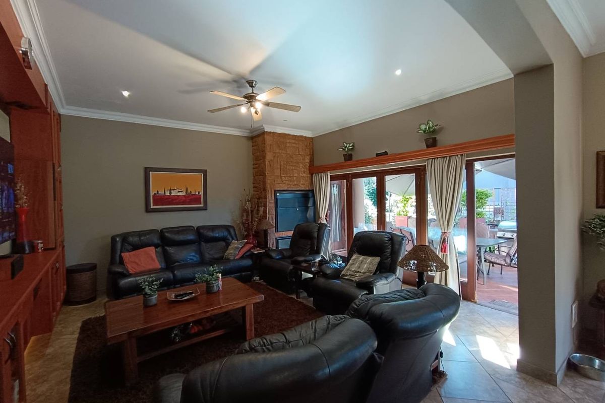 Spacious living room featuring a stone-clad fireplace, built-in cabinetry, ceiling fan, and large sliding doors providing direct access to the outdoor patio area.