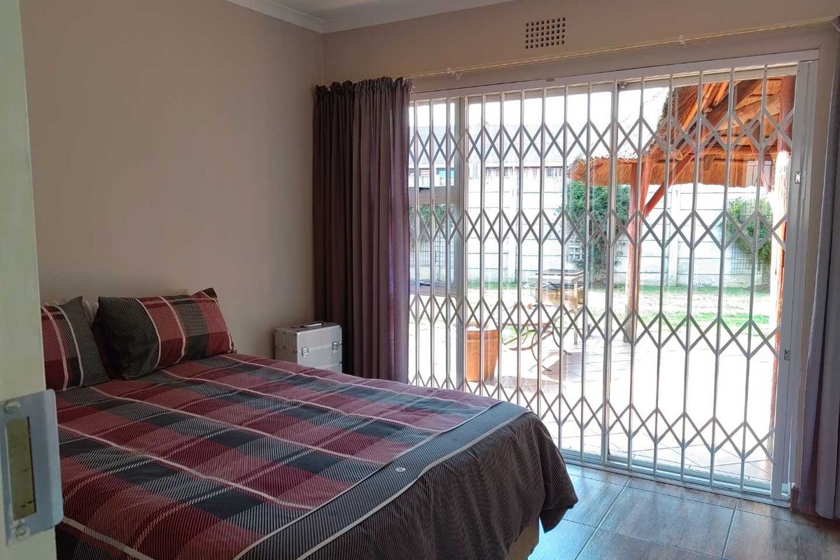 A bedroom featuring tiled flooring and a sliding glass door with a security gate, providing direct access to the outdoor patio area.
