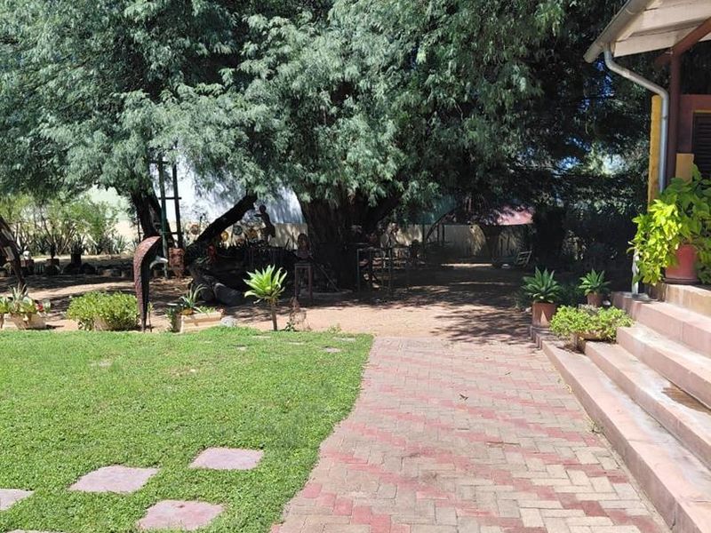 A spacious garden area featuring a paved walkway, manicured lawn, and concrete steps leading to the side of the property.