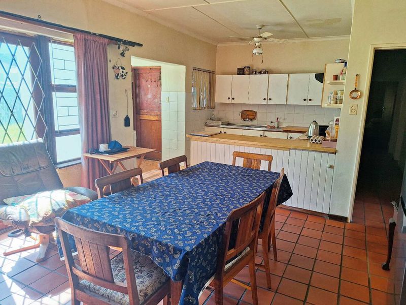 Open plan kitchen and dining area featuring tiled flooring, built-in cabinetry, and a breakfast counter, offering a functional layout with potential for modernization.