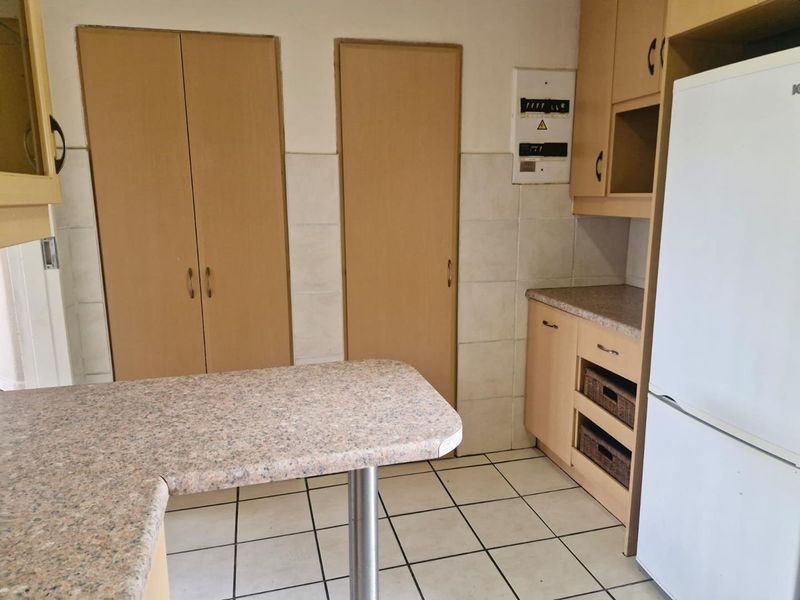 A functional kitchen area featuring laminate cabinetry, tiled flooring, and a breakfast counter, providing a practical layout for daily use.