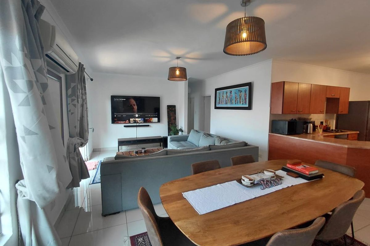 Open-plan living and dining area featuring tiled floors, split-system air conditioning, and a functional kitchen with built-in cabinetry and a breakfast bar.