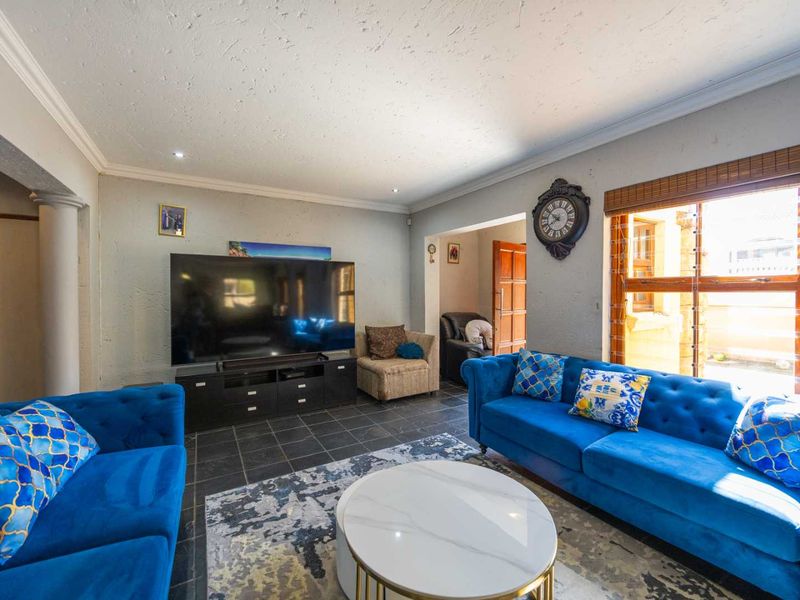 A comfortable living room featuring tiled flooring, recessed lighting, and crown molding, providing a functional space for relaxation and entertainment.
