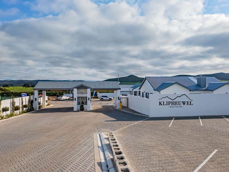 The entrance to Klipheuwel Estate featuring a secure gatehouse, paved driveway, and modern boundary wall with estate signage.