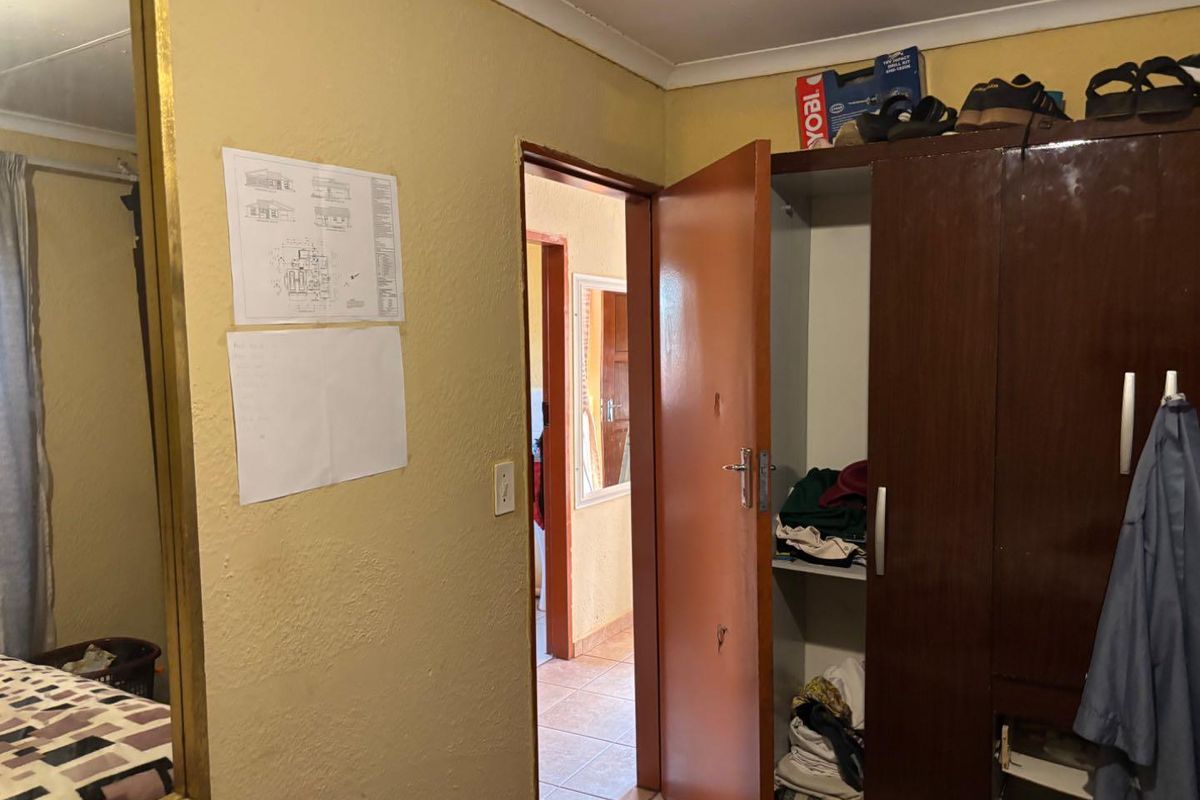 A bedroom interior featuring a built-in wardrobe and access to an adjoining hallway.