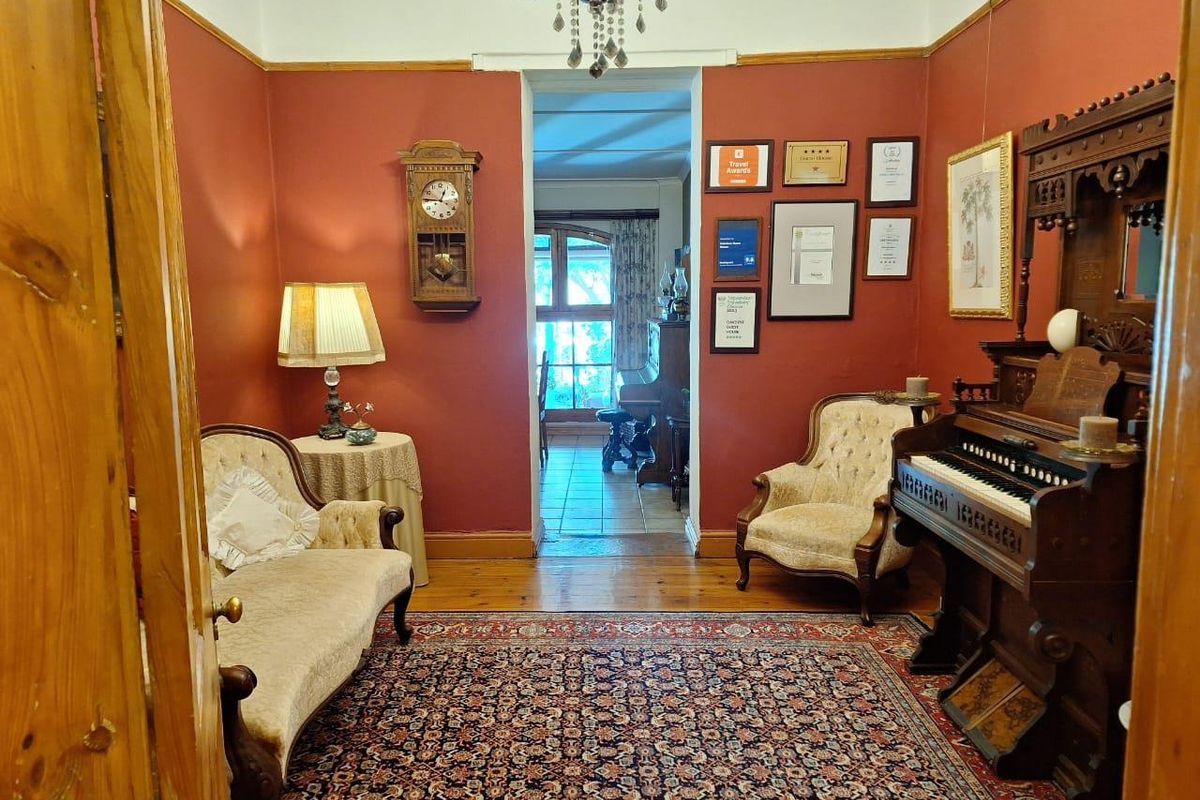 A traditional living room featuring hardwood flooring, high ceilings with a decorative chandelier, and a doorway leading to an adjacent room.