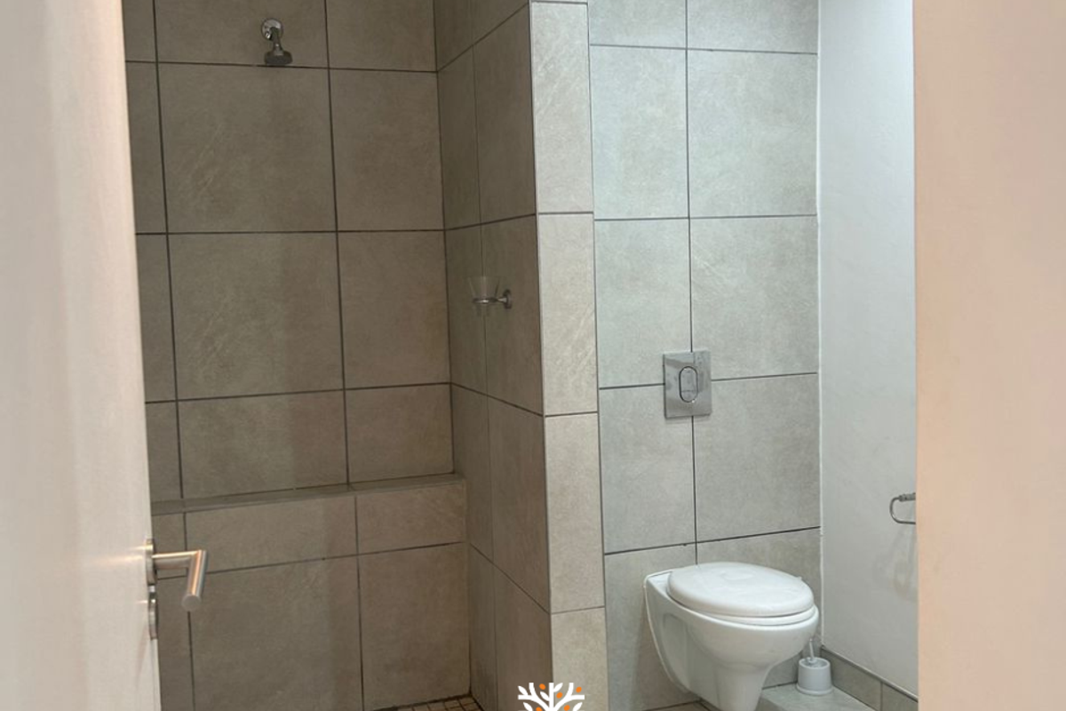 Modern bathroom featuring a walk-in shower with tiled walls and a wall-mounted toilet with a concealed cistern.