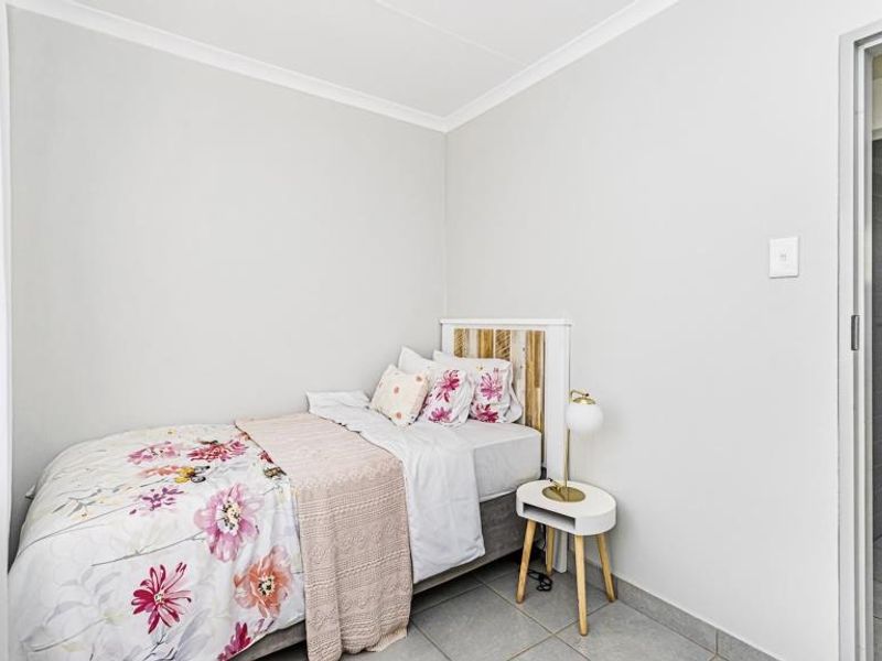A clean and well-maintained bedroom featuring neutral wall tones, tiled flooring, and coved ceiling detailing.