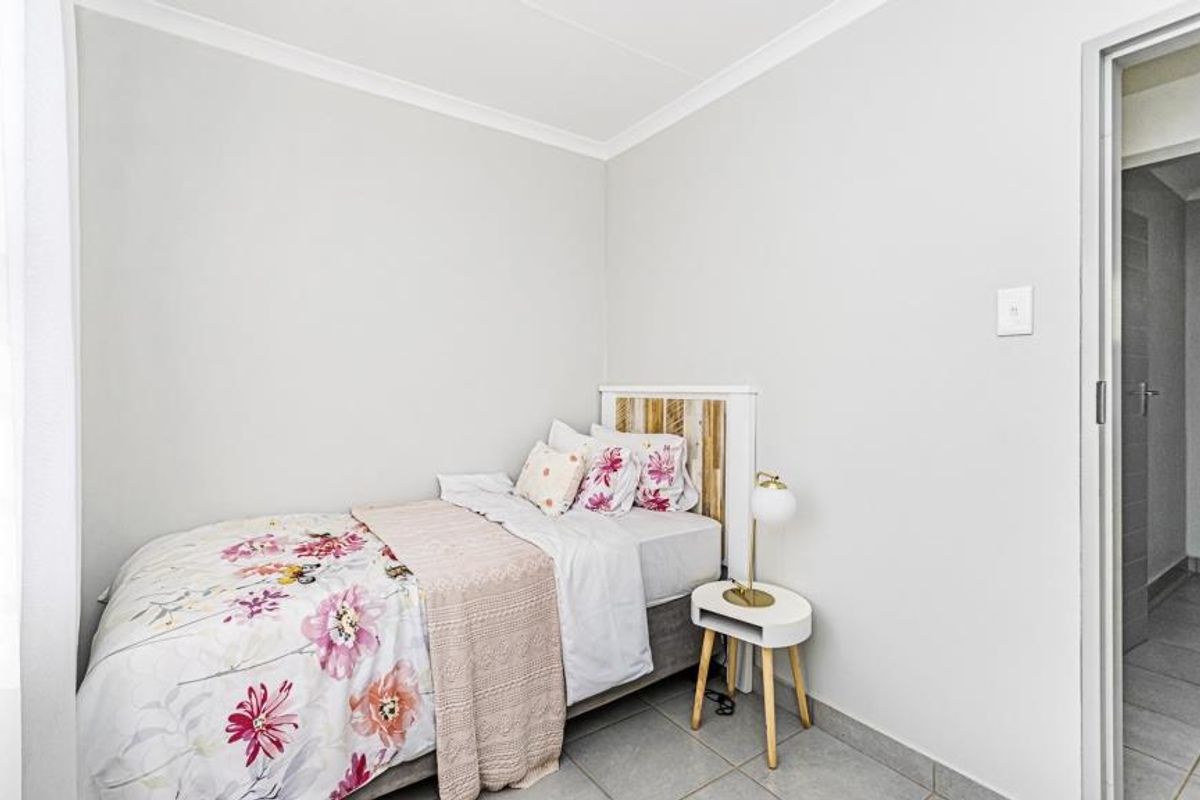 A clean and well-maintained bedroom featuring neutral wall tones, tiled flooring, and coved ceiling detailing.