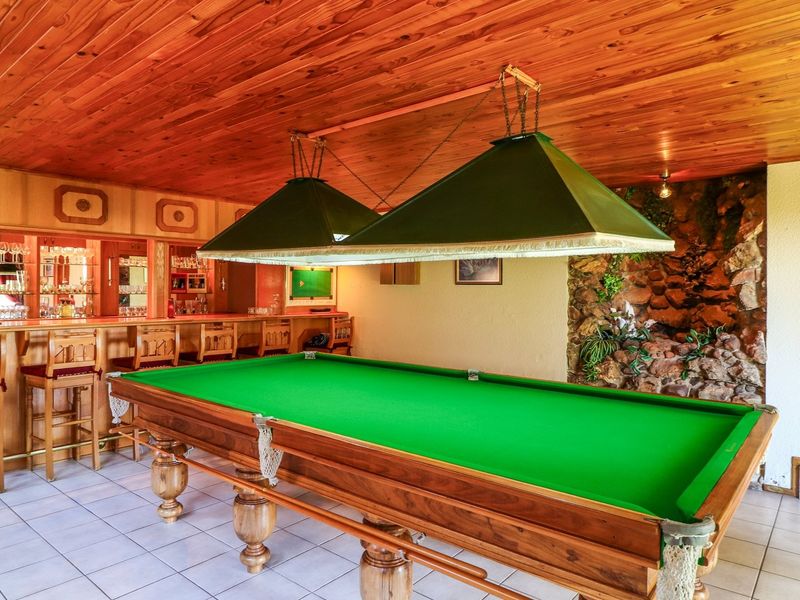 A dedicated bar area featuring a built-in wooden counter, timber ceiling, stone feature wall, and tiled flooring, ideal for entertainment.