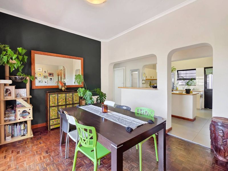 Open-plan dining area featuring classic parquet flooring and a convenient pass-through window connecting to the kitchen, creating a bright and functional living space.