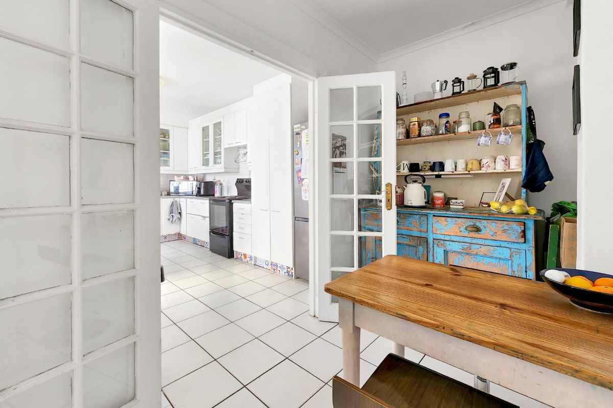 A functional kitchen featuring white cabinetry, tiled flooring, and classic french door access, offering a bright and practical layout for daily meal preparation.