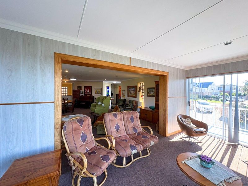 Spacious open-plan living area featuring wood-look wall paneling, a large timber-framed opening, and sliding glass doors leading to the exterior.