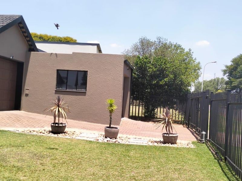 Front exterior view of the property featuring a paved driveway, garage access, and secure metal perimeter fencing.